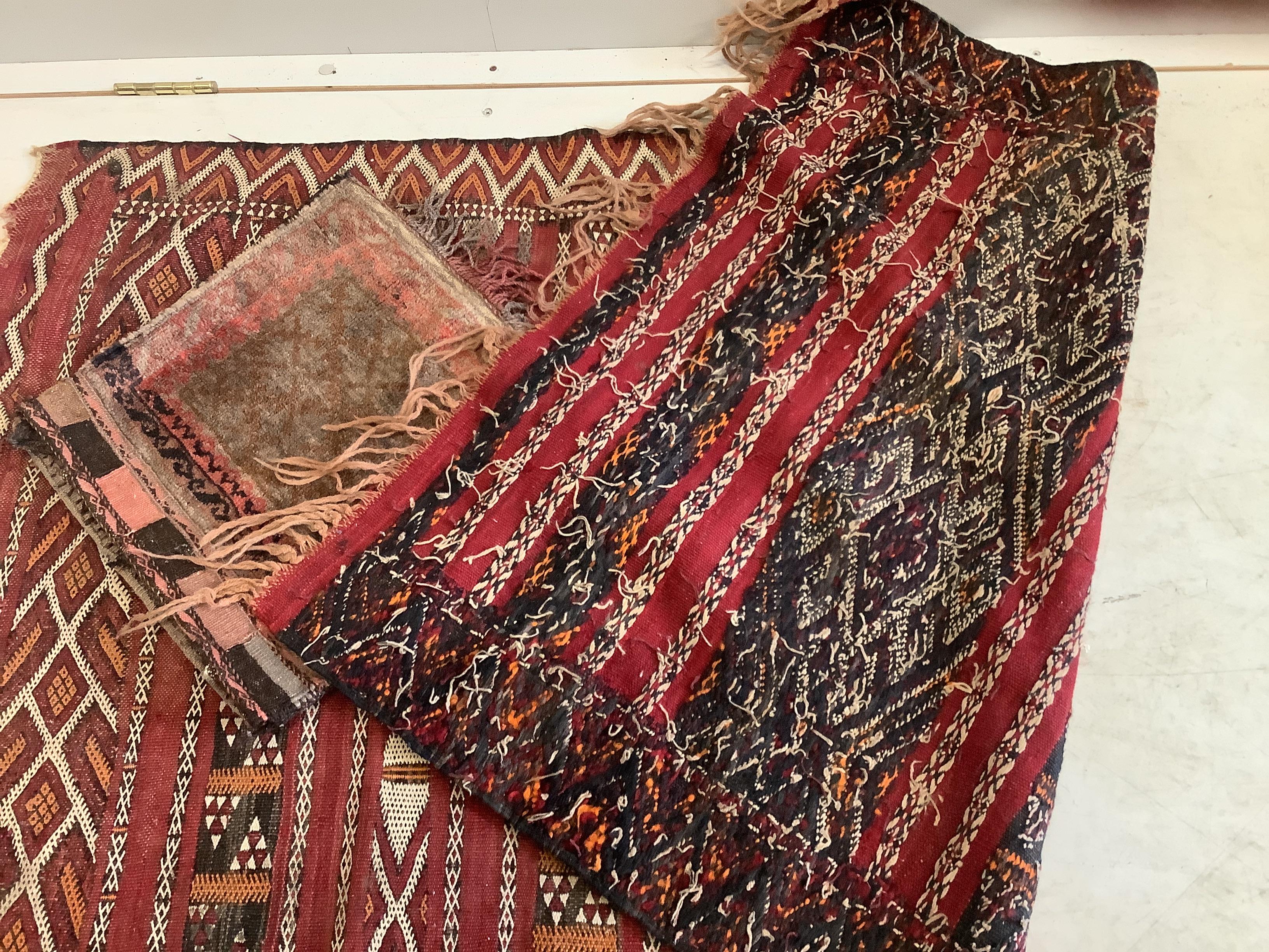 A Moroccan red ground geometric rug together with a saddle bag, larger 150 x 90cm